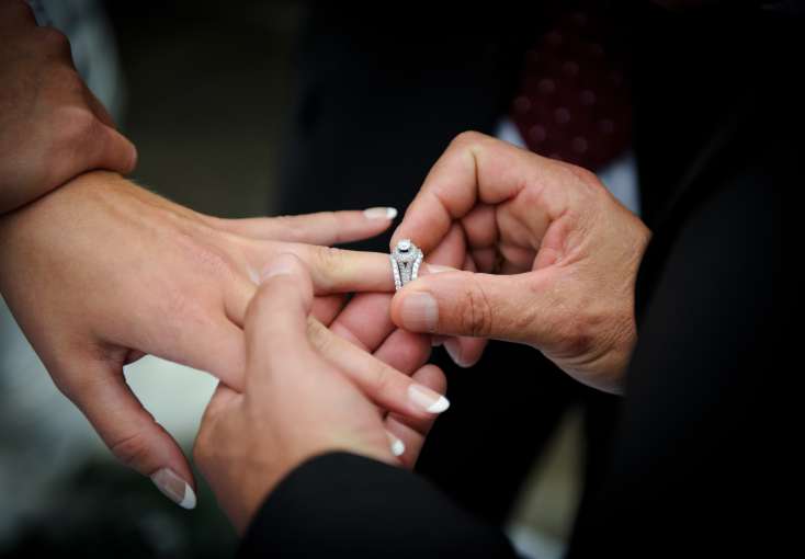 Groom putting wedding ring on brides finger