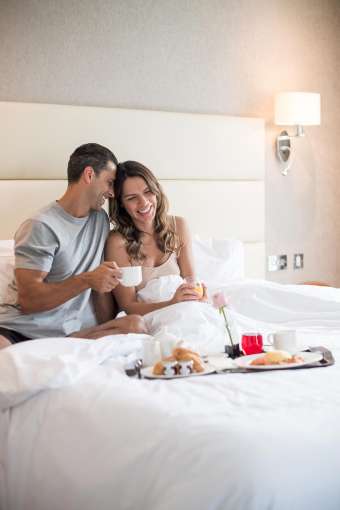 A couple enjoying breakfast in bed in the room at the Carlyon Bay Hotel