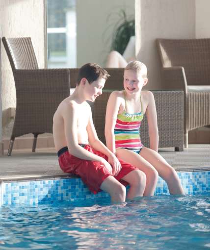 Family kids sat beside indoor pool