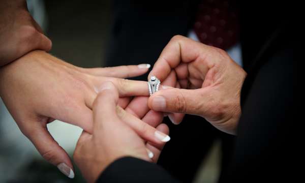Groom putting wedding ring on brides finger