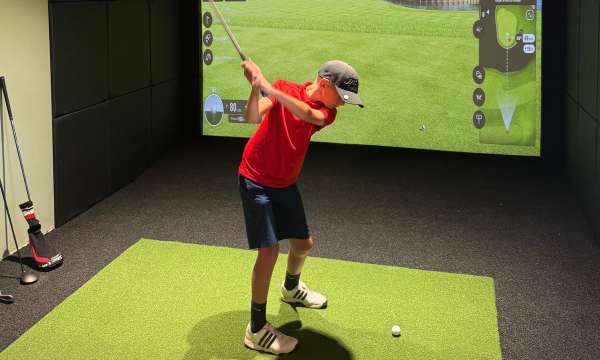 Boy swinging golf club in Carlyon Bay's Golf Club TrackMan Studio