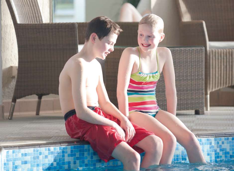 Family kids sat beside indoor pool