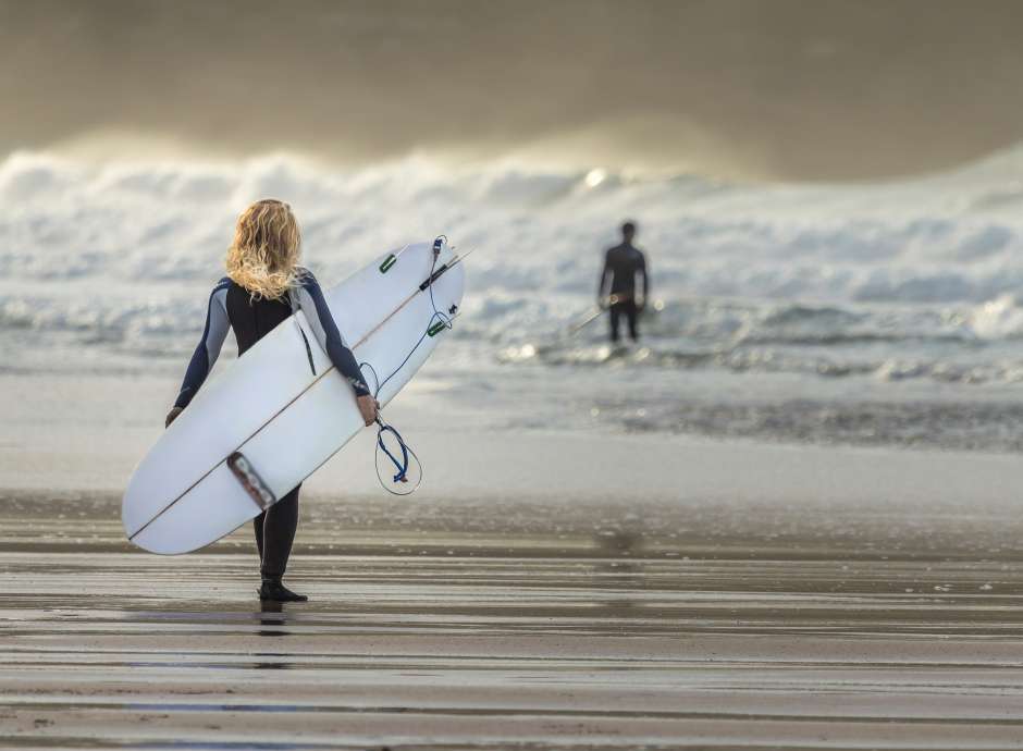 Girls walking into sea with surfboard