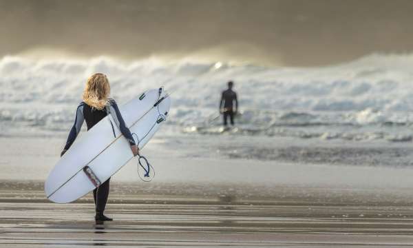 Girls walking into sea with surfboard
